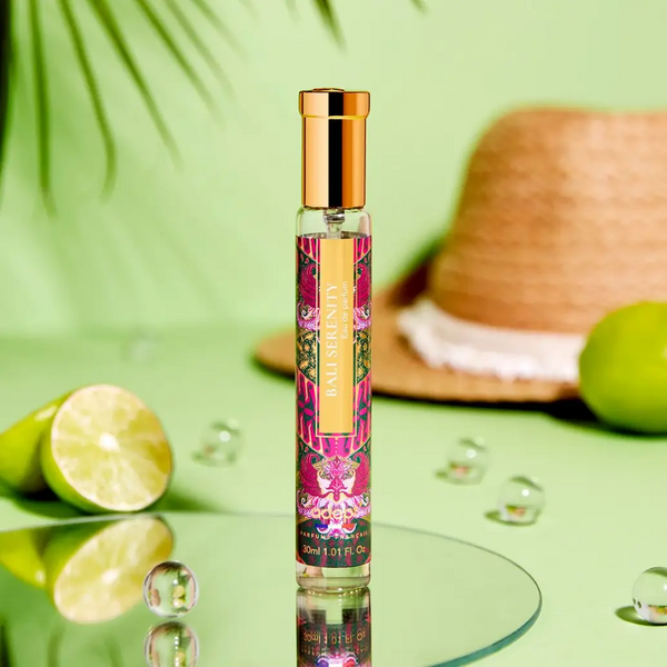 Adopt Bali Serenity eau de parfum in a clear bottle with a gold cap and a vibrant label, surrounded by limes and a straw hat