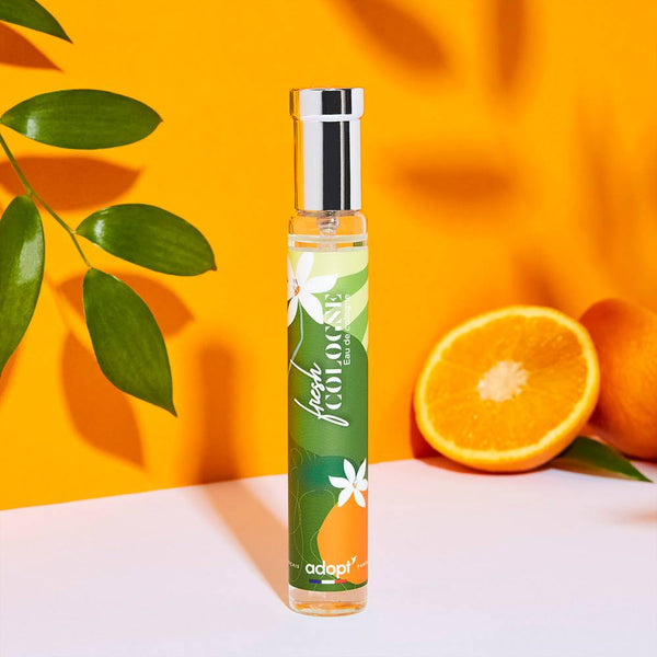 Adopt Fresh Cologne bottle with a green and orange label featuring white flowers,