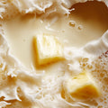 Adopt Fruit Shot Body & Hair Mist with pineapple chunks in a creamy, milky liquid, creating splashes and foam