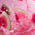 Adopt Fruit Shot Body & Hair Mist with watermelon slices and pink liquid splashing, creating a refreshing and vibrant scene