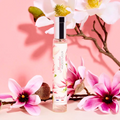 Adopt Magnolia Majestueux perfume bottle with a silver cap, surrounded by pink and white magnolia flowers on a pink