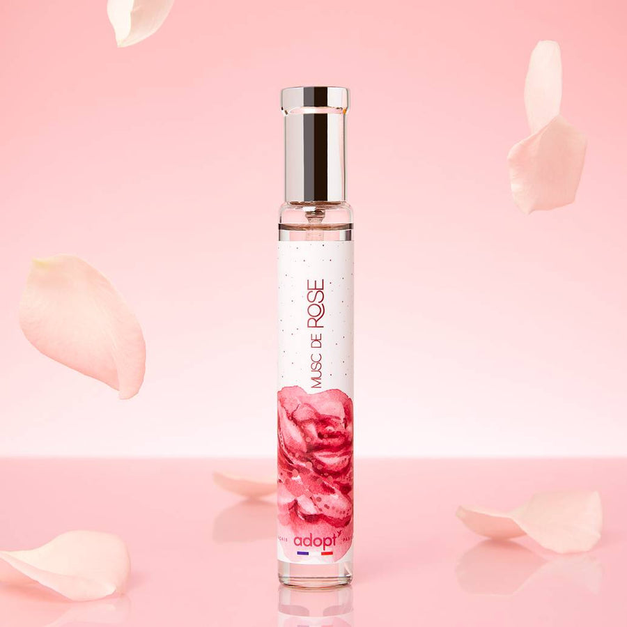 Adopt Musc De Rose perfume bottle with a pink rose design on a pink background with rose petals