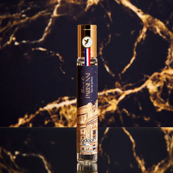 Adopt Nuit Parisienne Eau de Parfum in a sleek bottle with a gold cap and a French flag ribbon,