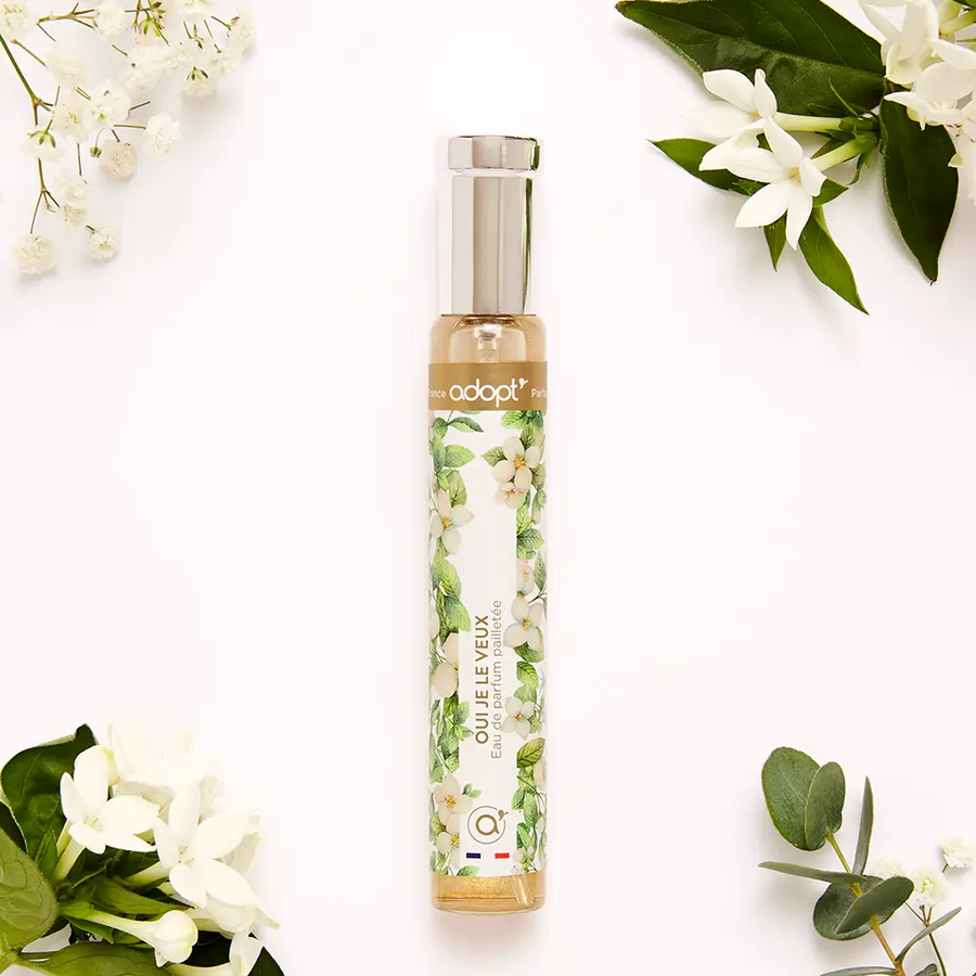 Adopt Oui Je Le Veux Eau de Parfum pailletée in a clear bottle with a floral design on a white background
