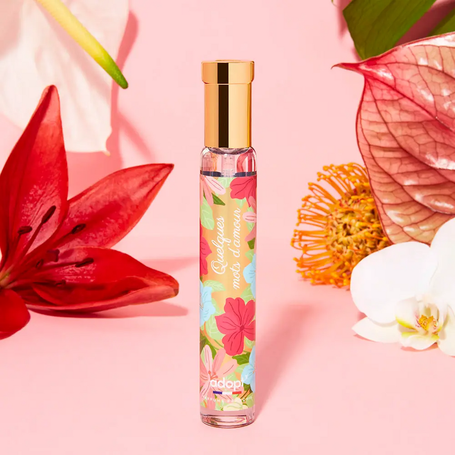 Adopt Quelques Mots D'Amour perfume bottle with a floral design, surrounded by red, white,