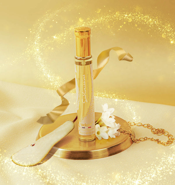 Adopt Sublimissime glittery eau de parfum with a golden ribbon, white flowers, and a pear slice on a gold tray