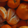 Adopt Tendre Iris fragrance with a close-up of orange citrus fruits and peeled segments,