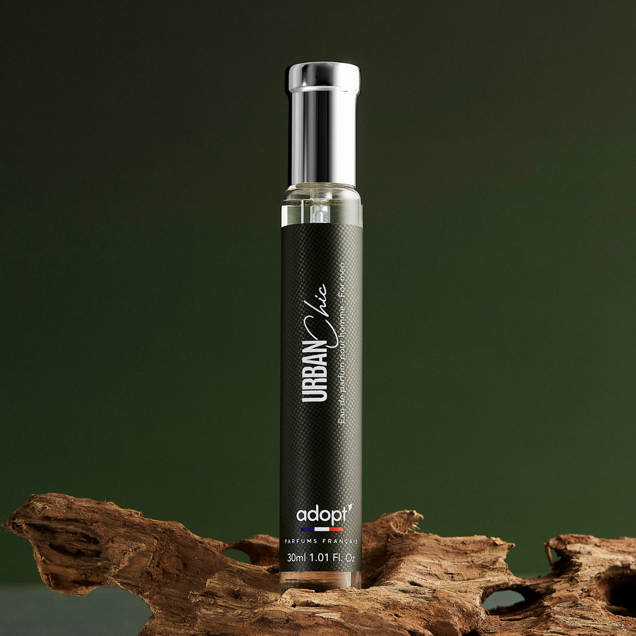 Adopt Urban Chic perfume bottle with a black label and silver cap, standing on a piece of natural wood