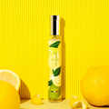 Adopt Yuzu Vivifiant perfume bottle with a gold cap, surrounded by fresh lemons and lemon peels on a yellow background