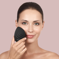 GESKE Sonic Facial Brush 5 in 1 in black, held by a woman on her cheek, showcasing its design and how it's used