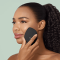 GESKE Sonic Warm & Cool Mask 9 in 1 in gray, held by a woman on her cheek during a skincare treatment