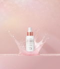 Pestlo Baby Collagen Glow Serum Mist bottle in a splash of pink liquid, highlighting its hydrating properties